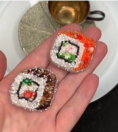 two small pieces of sushi on someone's hand in front of a plate