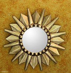 a gold sunburst shaped mirror mounted on a wall