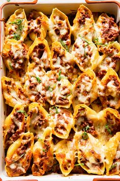 a casserole dish filled with stuffed shells and meat sauce, garnished with parsley