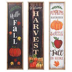 three wooden signs with pumpkins, apples and leaves painted on the sides of them