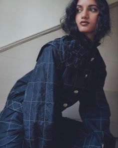 a woman sitting on the ground wearing a blue jacket