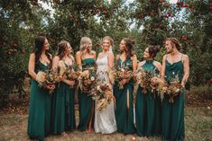 a group of women standing next to each other in front of an apple tree filled with apples