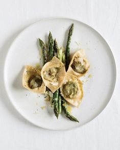 a white plate topped with asparagus and dumplings on top of a table