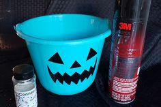 a blue bucket sitting on top of a table next to an empty bottle and glue