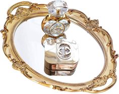 an ornate gold and clear mirror with a camera on it's side, in the shape of a heart