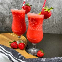 two glasses filled with red liquid and strawberries