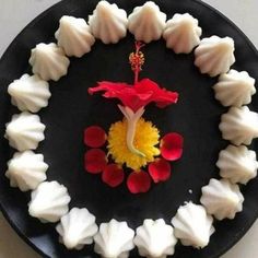 a black plate topped with white and red desserts on top of a table next to utensils