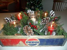 an old pepsi box with candles and pine cones