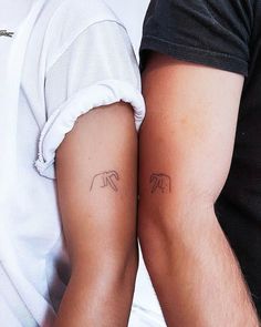 two people with tattoos on their arms and one is holding the other's arm