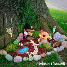 a fairy garden with gnomes and mushrooms in the grass next to a large tree