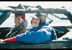 two men sitting in the back of a pick up truck with skis on their heads