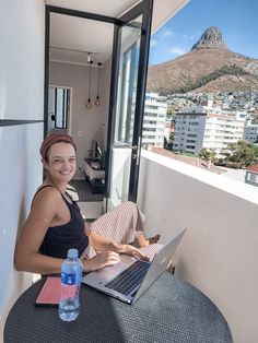 a woman sitting at a table with a laptop computer on her lap and water bottle in front of her