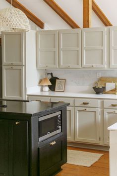 a kitchen with white cabinets and wood floors