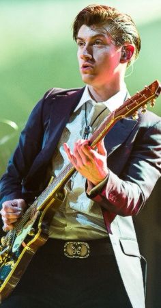 a man in a suit and tie holding a guitar