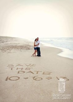 a man and woman standing on top of a sandy beach