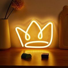 a light up crown sitting on top of a table next to a vase with flowers