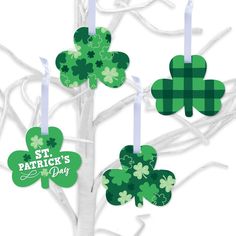 four green shamrocks are hanging from the branches of a tree with white candles in front of them