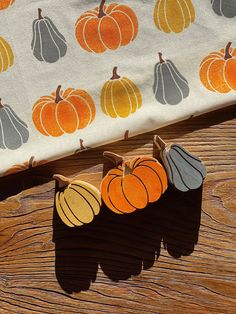 three small pumpkins sitting on top of a wooden table