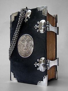 an open book with a chain attached to the front and back cover that is covered in metal