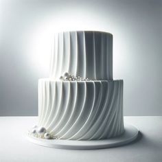 a three tiered white cake with pearls on the top and sides, sitting on a plate