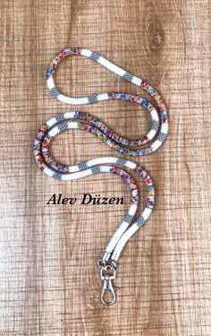 a white leash with multi colored beads and silver metal clasps on a wooden surface