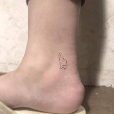 a small tattoo on the ankle of a woman's foot, with a finger pointing up