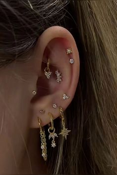 a close up of a person's ear with gold stars and chains on it