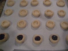 doughnut holes with jam in them sitting on a baking sheet ready to go into the oven