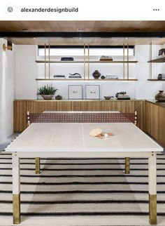 a ping pong table in the middle of a room with shelves on either side