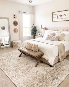 a bedroom with a bed, mirror and bench in the middle of the room on top of a rug