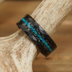 a black and blue ring sitting on top of a piece of wood