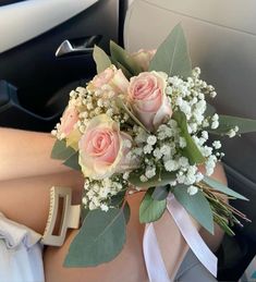 a bouquet of roses and baby's breath sits in the back seat of a car