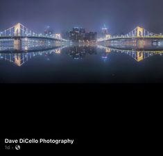 the city lights are reflected in the still waters of the river at night, while fog looms over the bridge