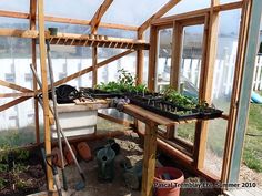 the inside of a greenhouse with plants growing in pots and shovels on the ground