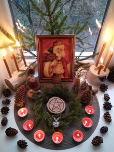 a table topped with candles and pictures next to a window filled with pine cones on top of it