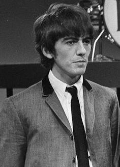 a man in a suit and tie standing next to a clock