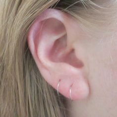 a close up of a woman's ear with two small hoops on it