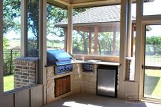 an outdoor kitchen with large windows and grill