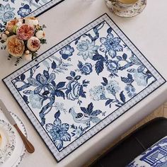 the table is set with blue and white plates, silverware and flowers on it