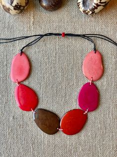 Handmade in Ecuador Necklace Length: Adjustable Length 14 -31 Inches Due to this item being handmade and the nature of the Tagua Nut the size and the color may vary from piece to piece Adjustable Pink Resin Necklace, Adjustable Multicolor Nature-inspired Jewelry, Handmade Red Nature-inspired Necklace, Pink Bohemian Resin Jewelry, Bohemian Pink Resin Jewelry, Adjustable Red Nature-inspired Jewelry, Handmade Pink Nature-inspired Necklace, Adjustable Bohemian Resin Jewelry, Red Adjustable Cord Jewelry For Beach