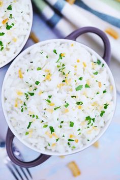 two white bowls filled with rice and garnished with parsley