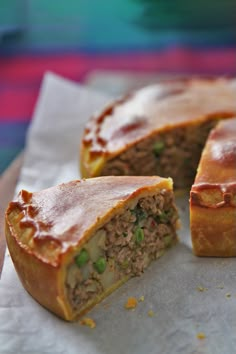 a meat and vegetable pie cut in half on top of wax paper with one slice missing