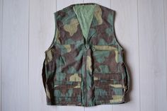 Very strong and firm vintage camouflage ammo vest.  It has zipper closure and additional large pocket on the back. Almost ideal vintage condition! Size : seems like women's (XL) & men's (L) Vintage condition on a scale 1-10 is 9 Measurements: Length: 73 cm/ 29" Shoulder to shoulder: 43 cm/ 17" Chest: 112 cm/ 44" Fabric: cotton Brand: Authentic Military More vintage vests here: https://www.etsy.com/dk-en/shop/TumbleweedsATTiTUDE?section_id=26366388 Whole shop here: https://www.etsy.com/shop/TumbleweedsATTiTUDE KEEP IN MIND: Photo might be slightly different from actual item in terms of color due to the lighting during photo shooting or your monitor's display. IMPORTANT NOTE: Item is shipped from eastern Europe, Latvia, which usually doesn't more than 10 business days to reach US. If purchas Vintage Vests, Combat Jacket, Hunting Vest, Vintage Vest, Mens Vests, Vests Mens, Vest Outfits, Eastern Europe, Large Size