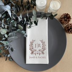 a place setting with candles, greenery and an embroidered napkin that says jr on it