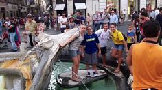 some people are standing around in front of a fountain with a large animal on it