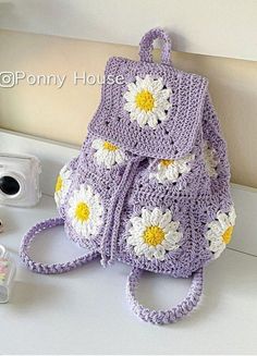 a crocheted backpack sitting on top of a counter next to a small camera