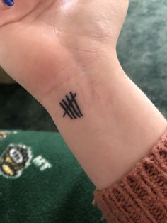 a woman's wrist with a small black tattoo on her left hand and an arrow in the middle