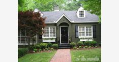 a green house with white windows and black shutters on the front door is shown