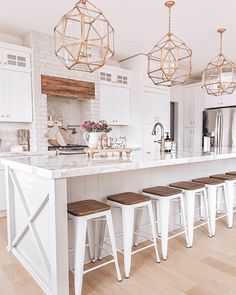 a kitchen island with stools in front of it and lights hanging from the ceiling