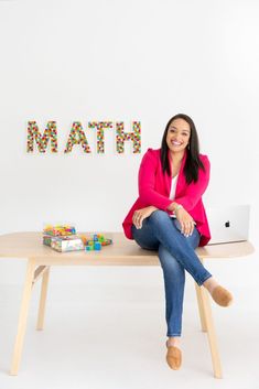 a woman sitting at a table with a laptop and toys in front of her that says math